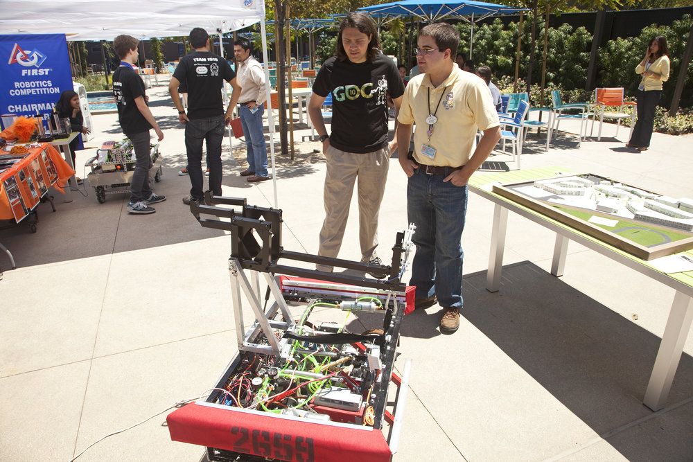 Imagineers looking at a FIRST robotics creation.