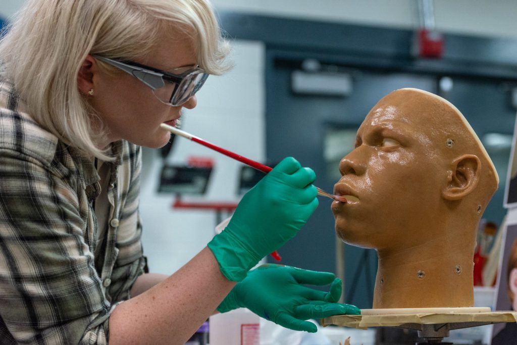 An Imagineer painting a sculpture model.