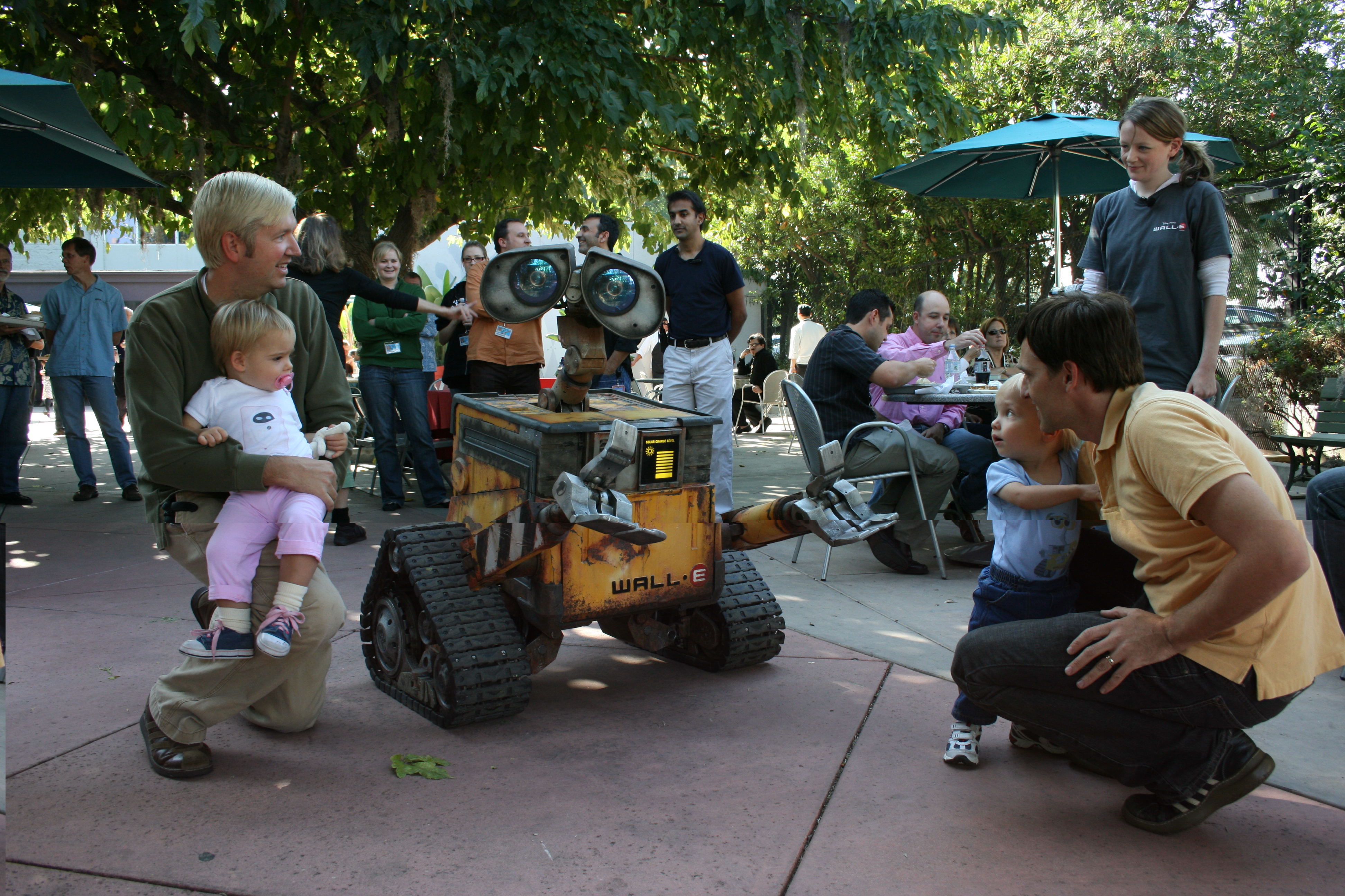 Imagineers and family interacting with the WALL-E animatronic figure.