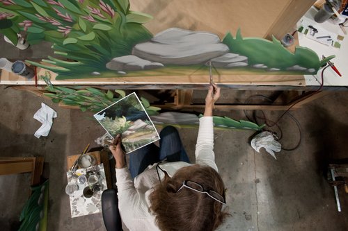 Imagineer painting a mural.