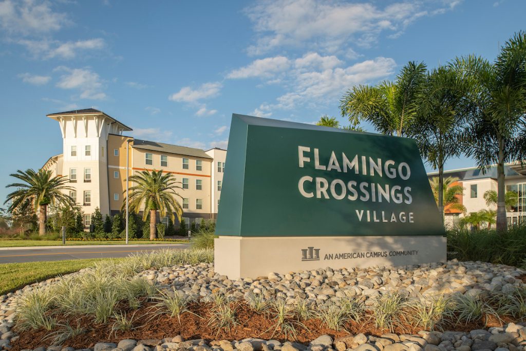 Photo of the main entrance sign to Flamingo Crossings Village in front of one of the apartment buildings