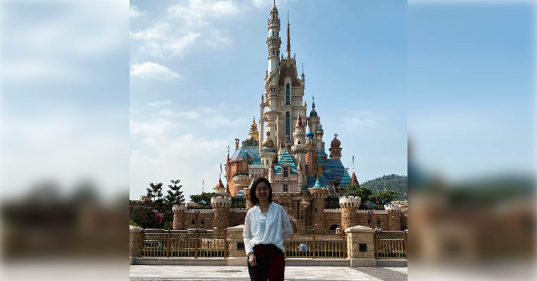 Phyllis Ma in front of the Hong Kong Disneyland Resort Castle