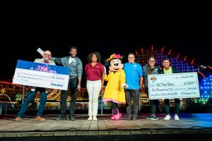 Minnie Mouse, Disney and Second Harvest employees holding checks for 100,000 and 5,000 in front of Incredicoaster