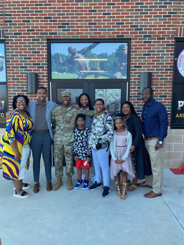 Photo of Jonathan Williams and eight family members. His son stands in the middle of everyone wearing him ROTC uniform.