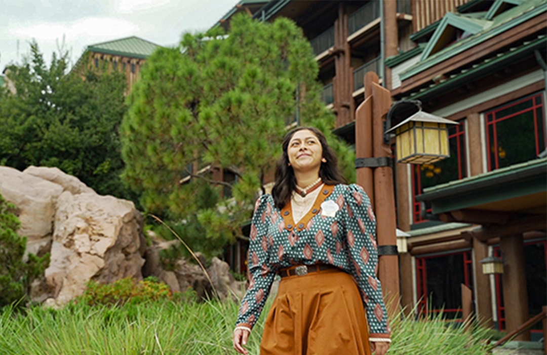 Disney college program female cast member smiling while walking in front of a Walt Disney World Resort