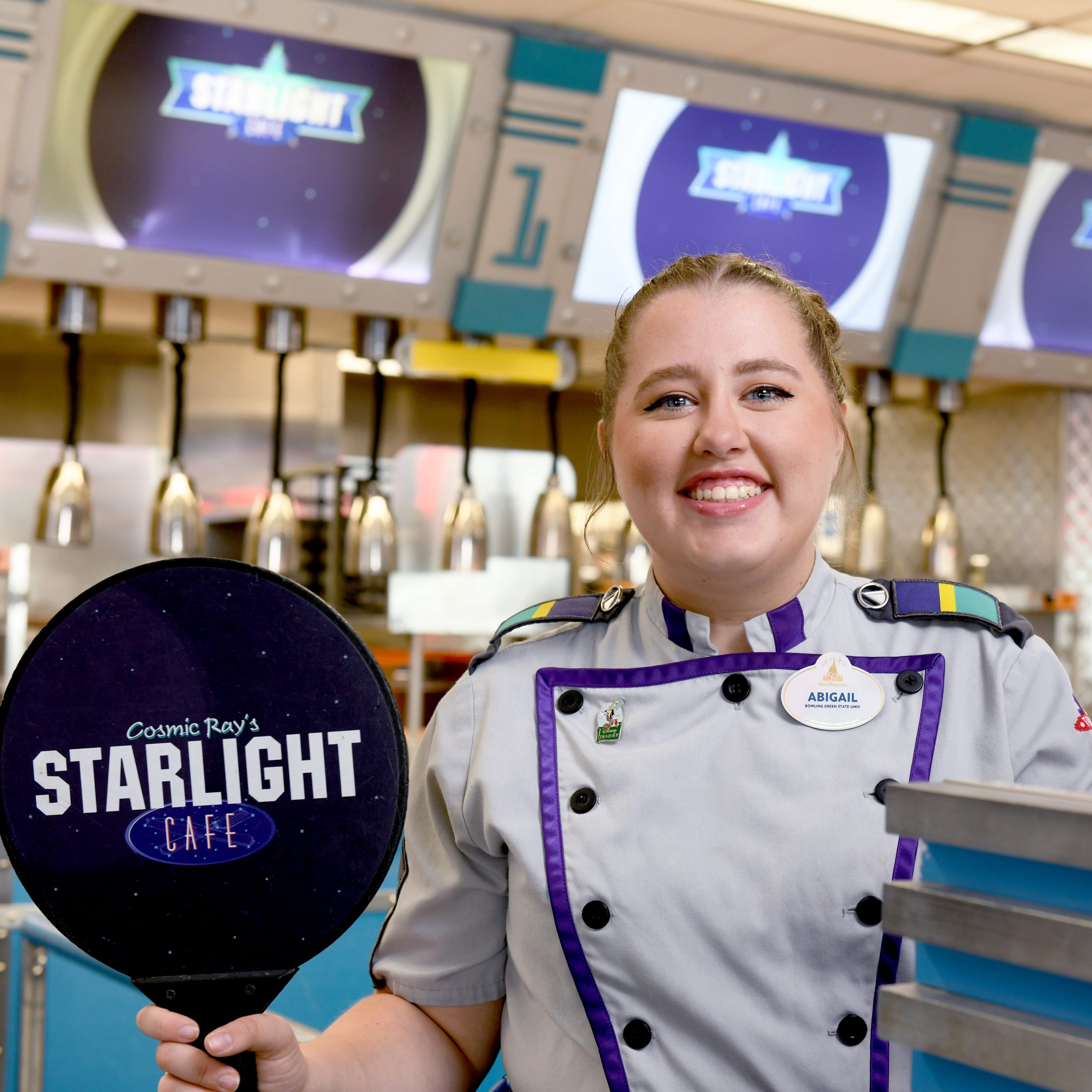 Female Disney College Program participant smiling while holding up a paddle for the Starlight Cafe