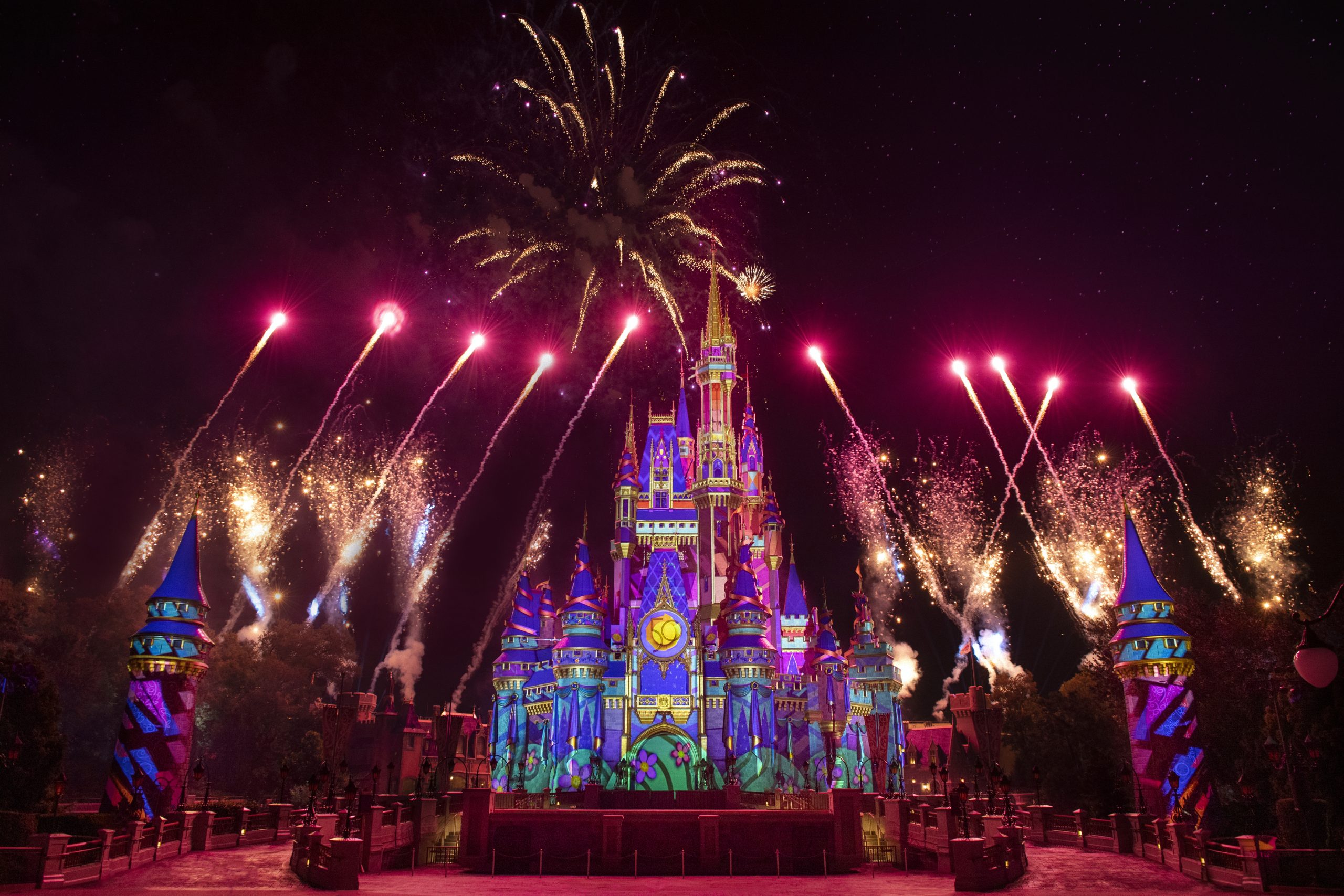 Cinderella's Castle at Magic Kingdom lit up while colorful fireworks surround