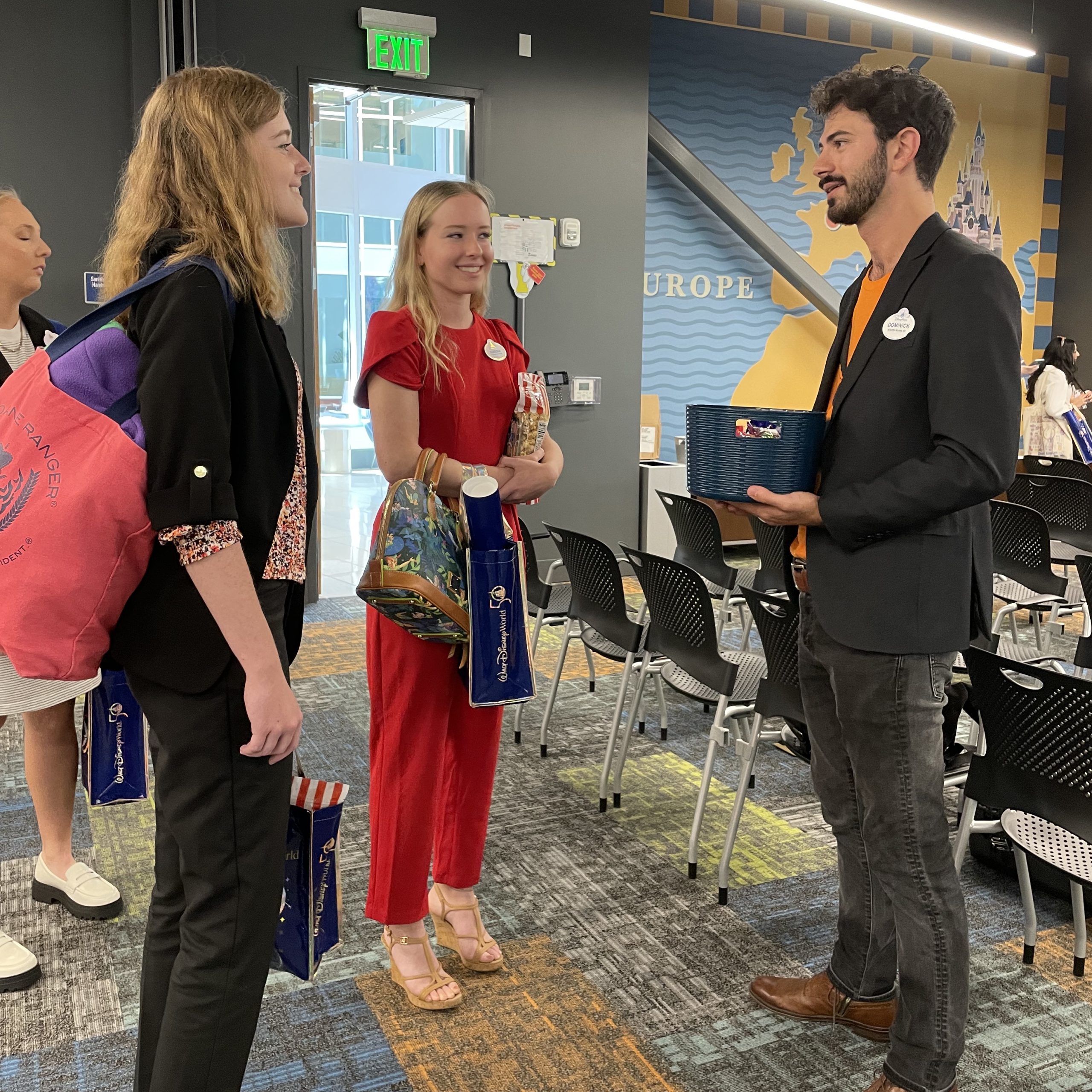 Four Disney College Program participants dressed in business clothing standing in a group talking at a networking event