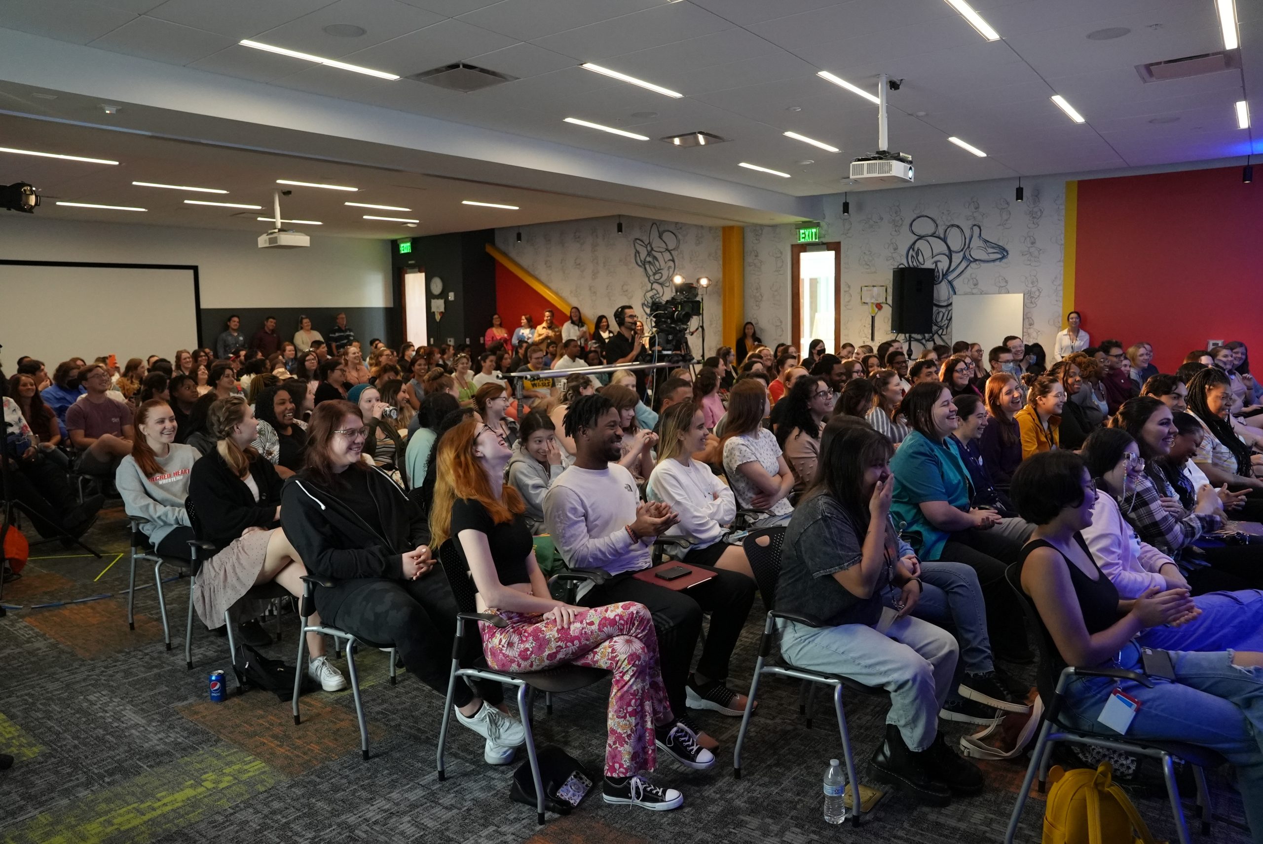 A large room full of Disney Programs participants sitting and smiling during a Disney programs learning session