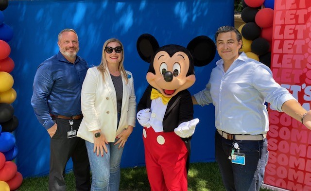 Daniel poses next to Mickey Mouse and two coworkers.