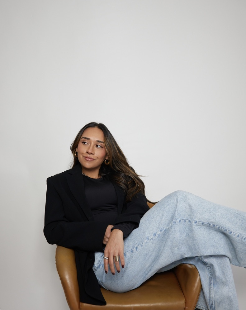 Celene smiles while sitting on a chair.