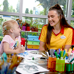 woman chatting with a child while coloring pages
