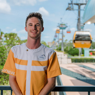 man posing in front of the Disney Skyliner