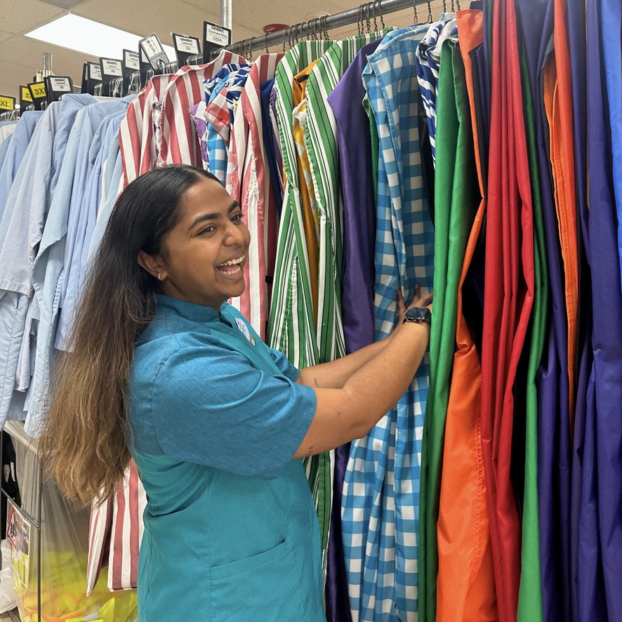 woman flipping through costume garment bags while smiling at the camera