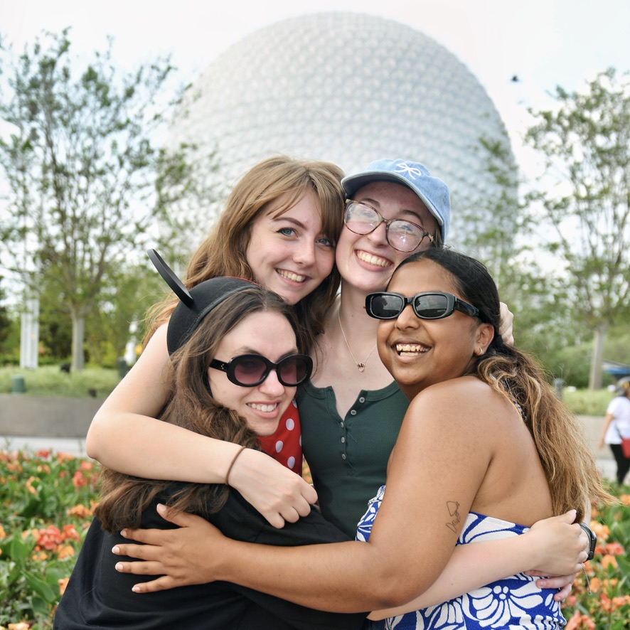 group of friends hugging and smiling at EPCOT