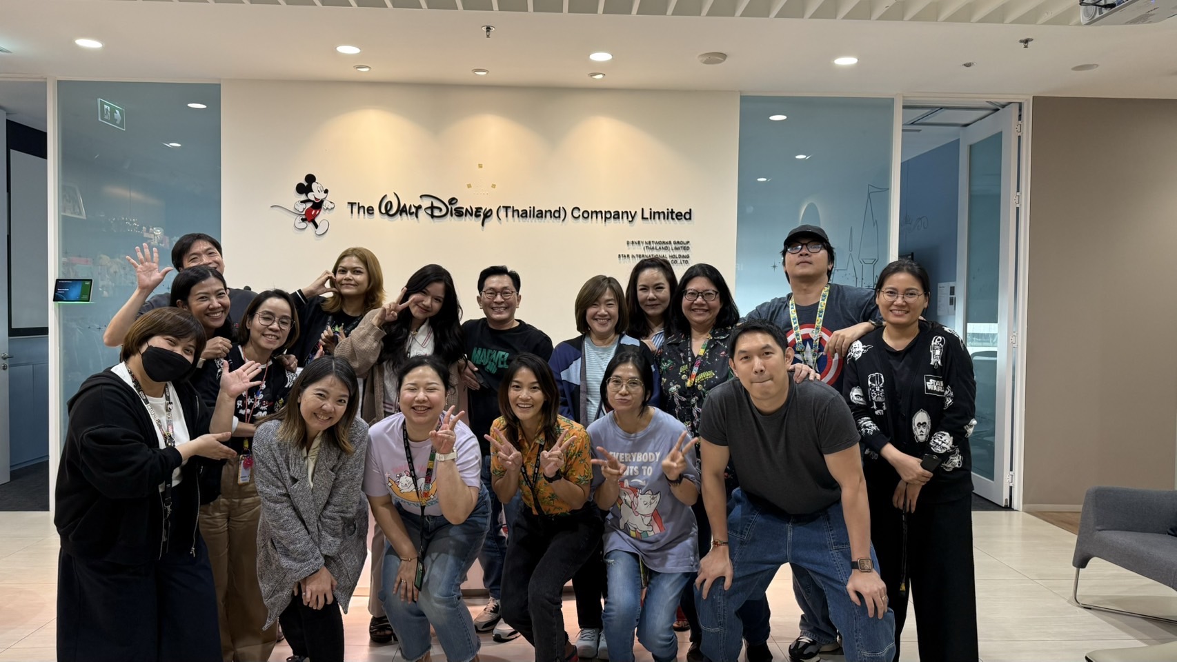 Group photo in front of The Walt Disney Company Thailand wall, showcasing team presence at the corporate office.