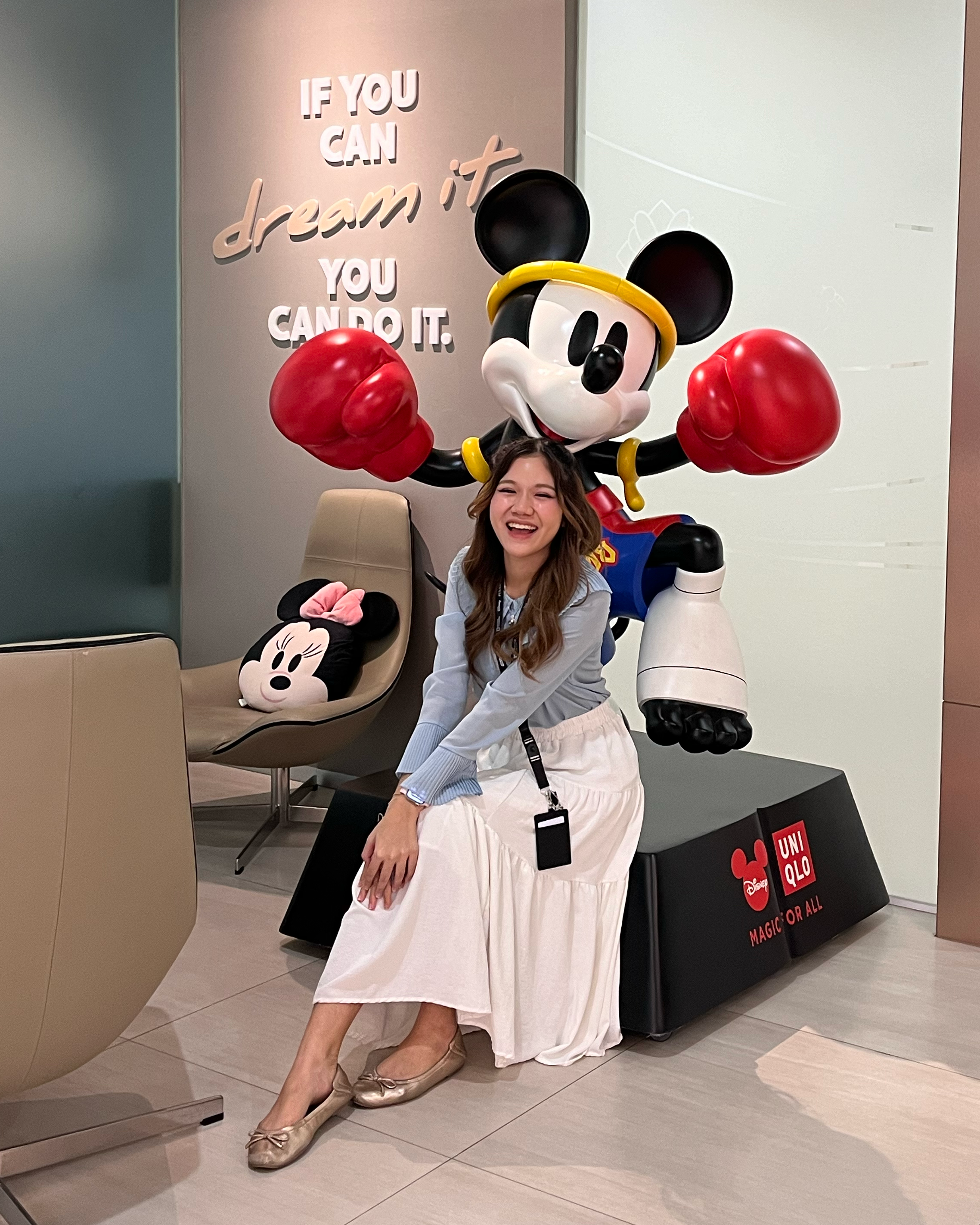 Person sitting in front of a large Mickey Mouse statue with red gloves, beneath the quote “If you can dream it, you can do it.”