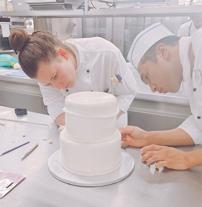 Pastry Chefs deep in focus while training on a wedding cake design.
