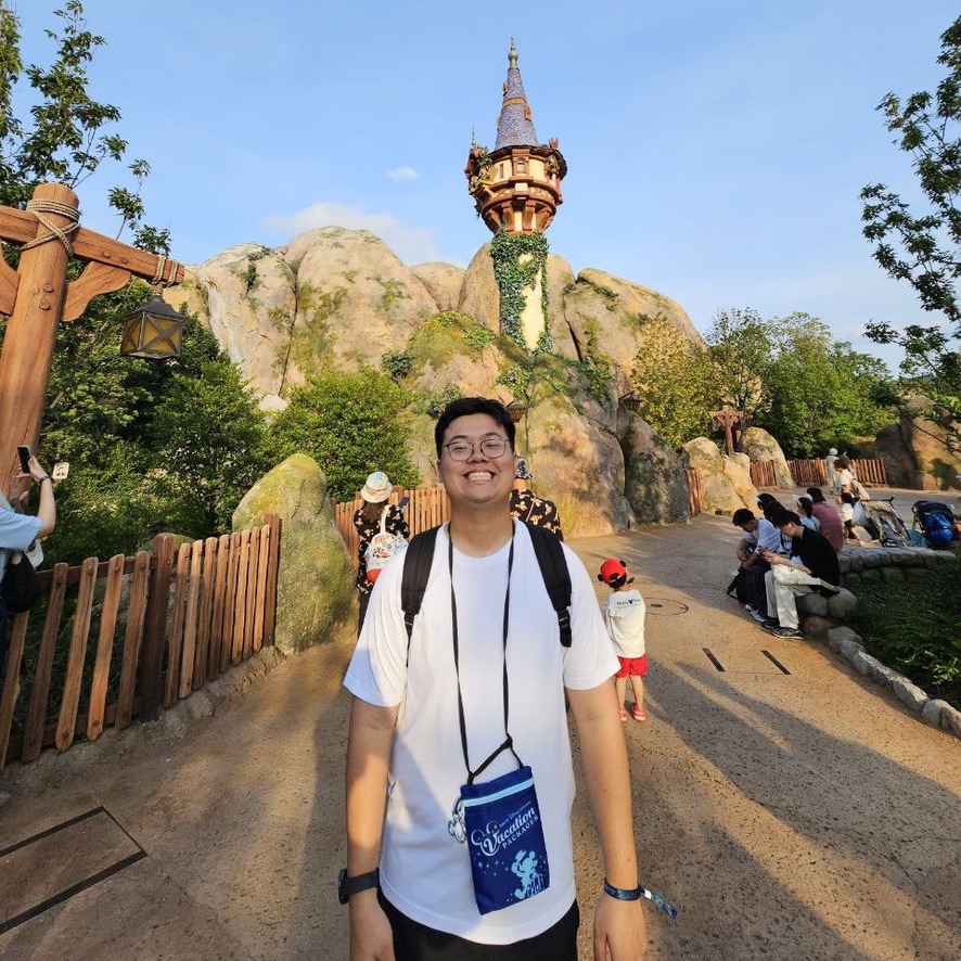 A0B28B4B-E56F-4DE9-BBA4-FD84C5D5DB0E_1_105_c man standing in front of the tower from Tangled in a Disney theme park