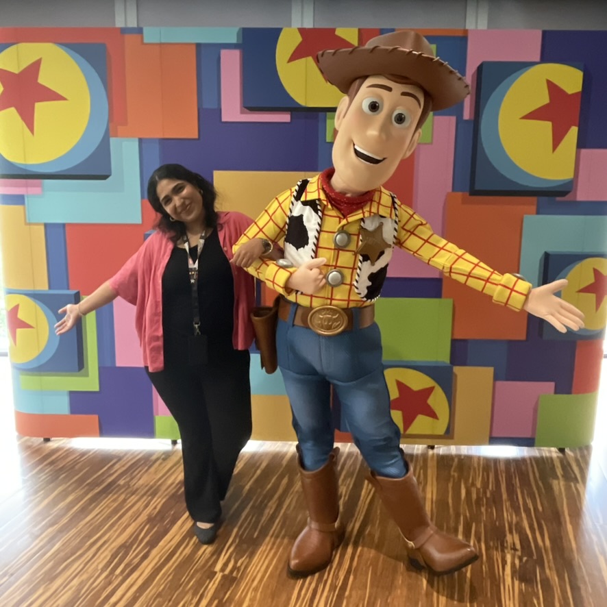 CDD03BC7-CADB-49A1-8756-DFEB70100736_1_105_c A person poses with Woody from Toy Story against a colorful background.