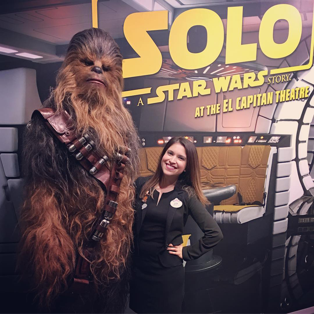 Woman posing in front of a “Solo: A Star Wars Story” promotional backdrop at the El Capitan Theatre with Chewbacca.