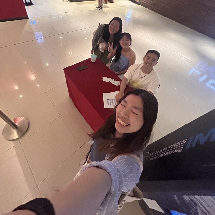 E559F86C-C98B-4FAA-B34A-0631D1B38A73_1_105_c Four people sit around a red table smiling and making peace signs, with an IMAX logo visible on the floor.