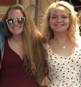 Two people are smiling together, and one of them is wearing sunglasses.