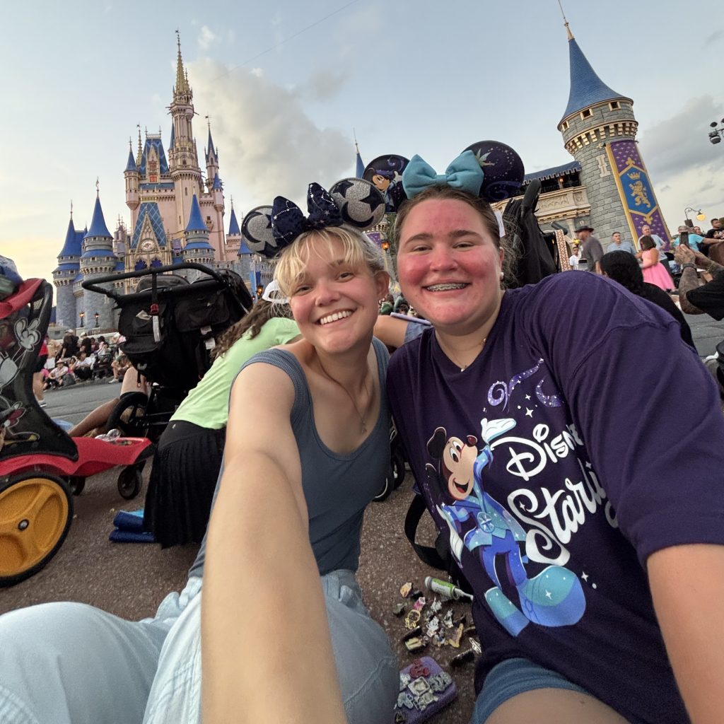Two people taking a selfie in front of Cinderella's Castle at Disney World.