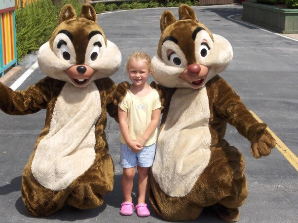 A child is posing between the characters Chip and Dale.