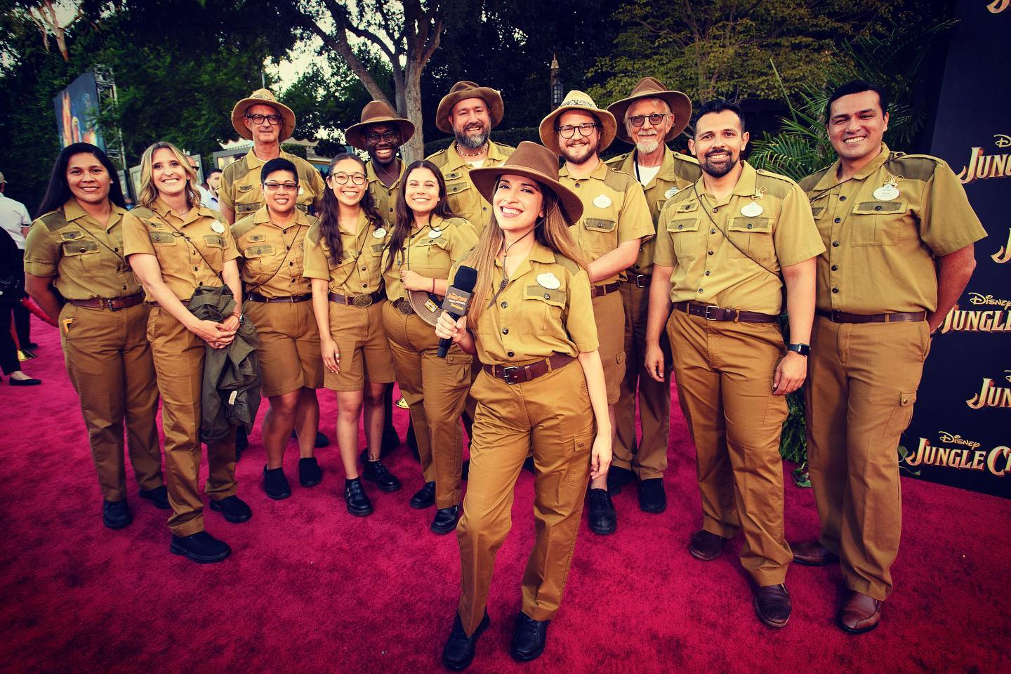 Group of Disney Jungle Cruise skippers in themed khaki uniforms posing together on a red carpet