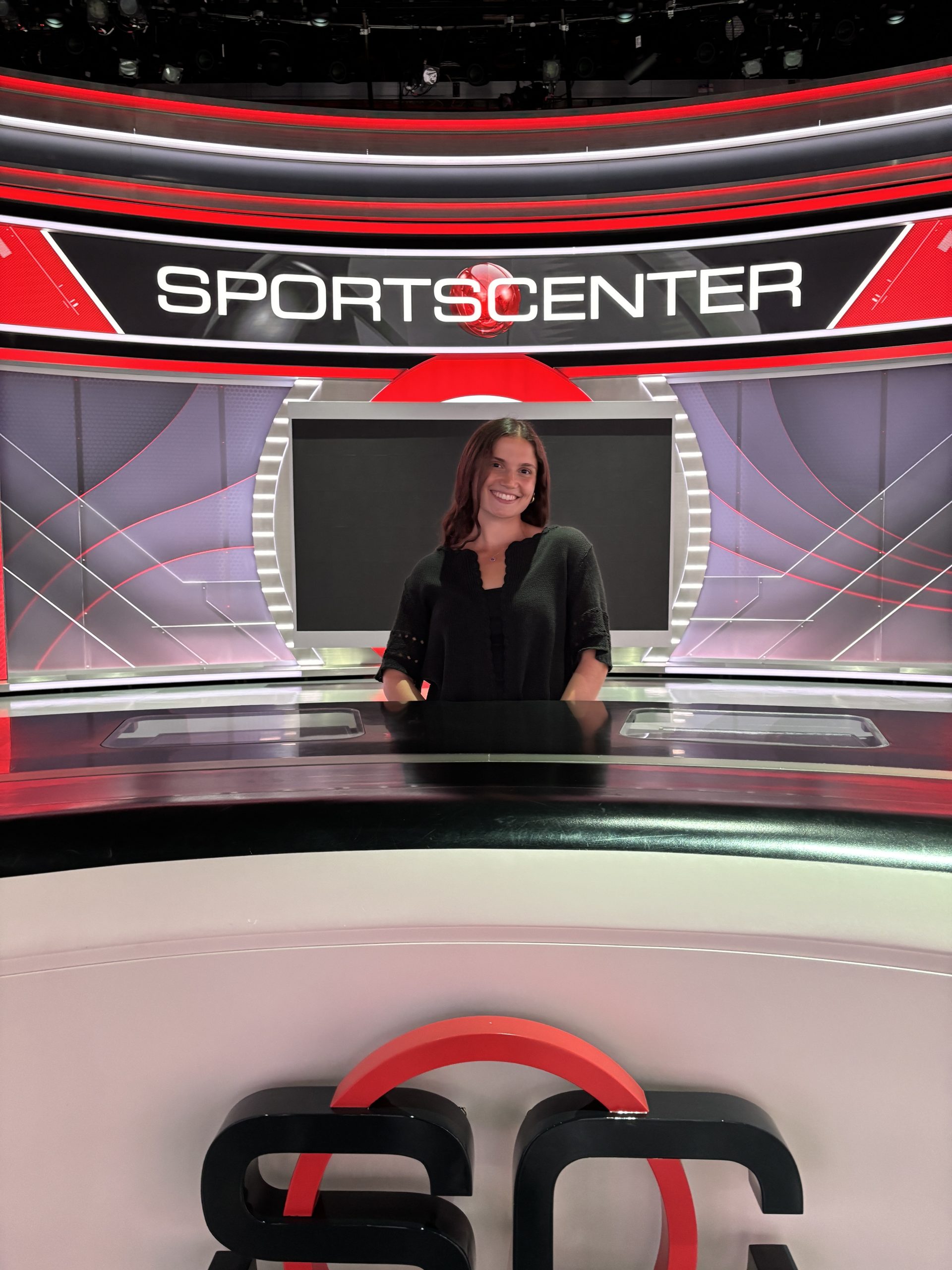 Person standing behind the SportsCenter anchor desk in a modern studio, highlighting ESPN’s broadcast innovation and sports journalism.