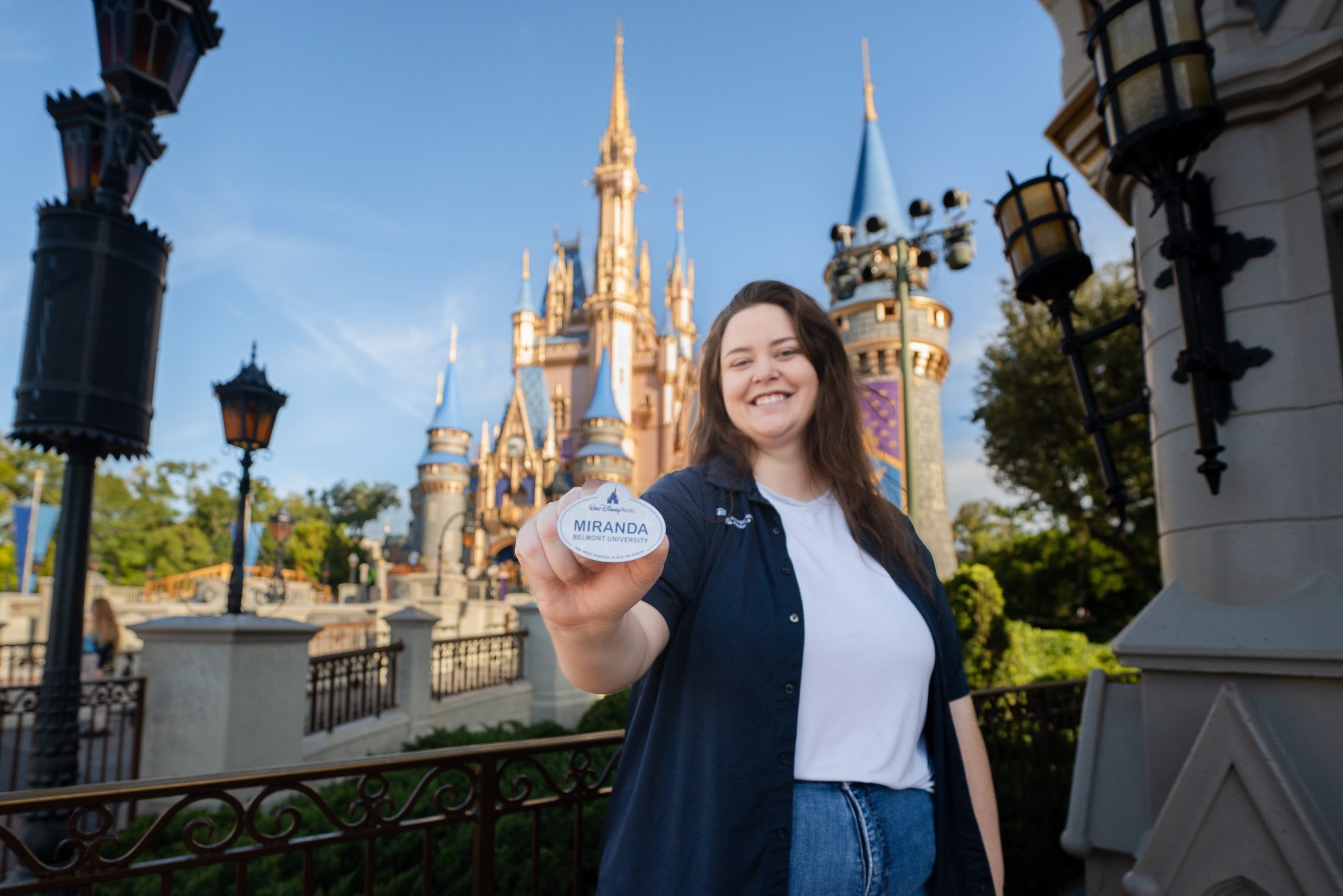 Person holding a name tag toward the camera with a castle in the background.
