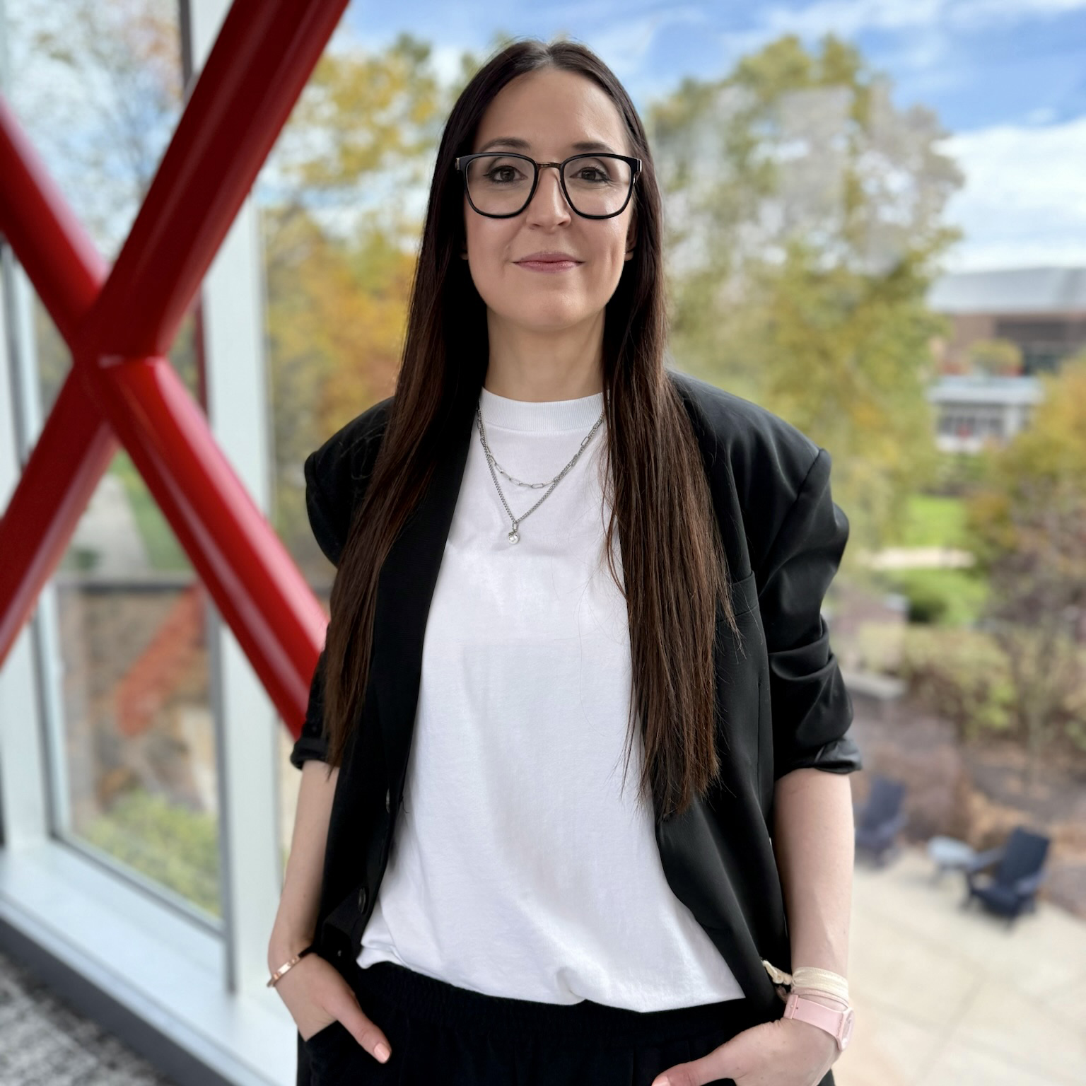 ESPN Creative Director standing indoors near large red beams and glass windows