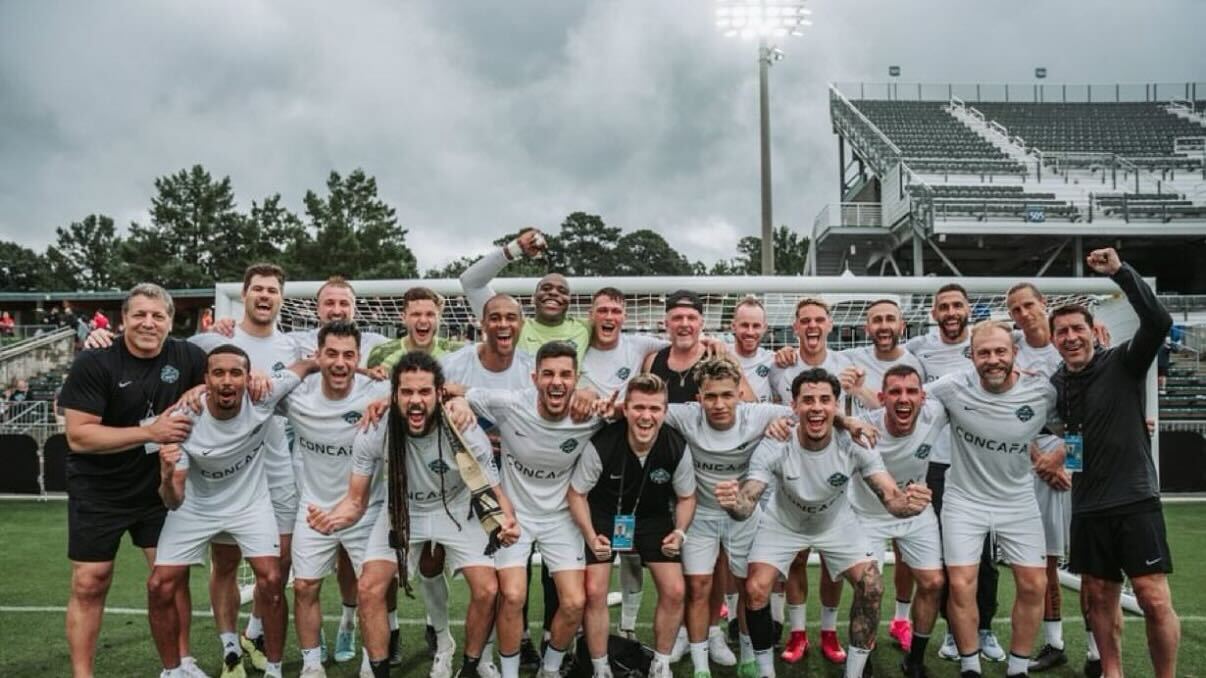 Group of soccer players and staff posing together on a field, celebrating teamwork and ESPN’s coverage of international sports.