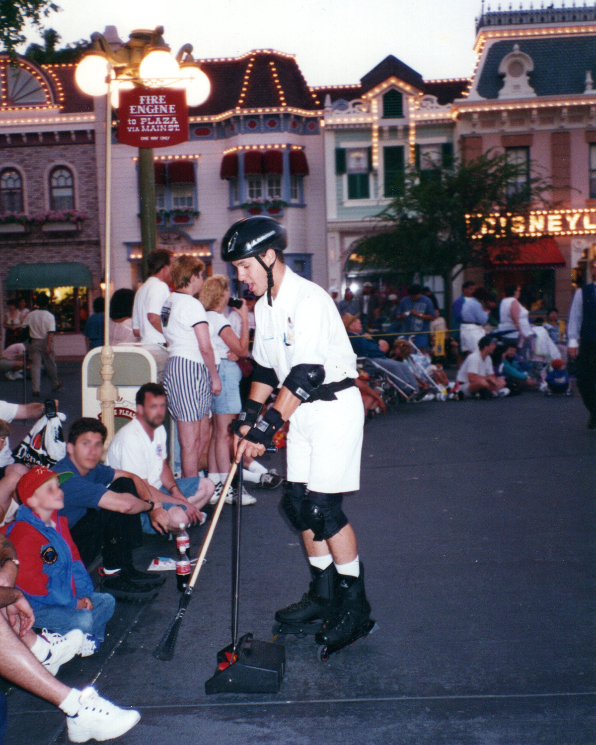 Disney cast member on Main Street, U.S.A. during park operations, showcasing teamwork and guest experience.