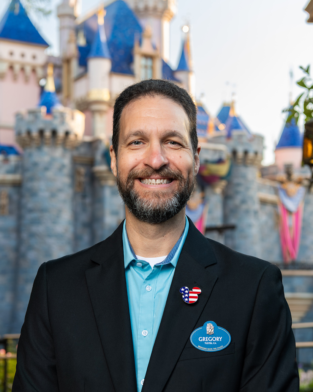 Disneyland Resort cast member poses in front of Sleeping Beauty Castle, representing long‑term career development and project management at Disneyland Park.