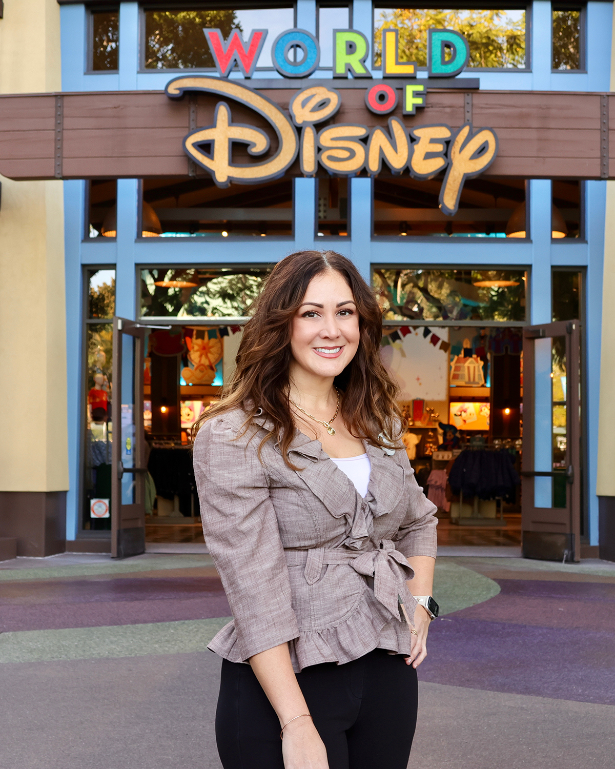 Disney cast member stands outside the World of Disney store in the Downtown Disney District at Disneyland Resort, highlighting career growth and retail operations.