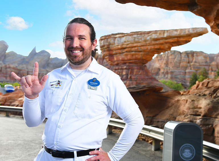 Male custodial cast member smiling outside in front of Cars Land