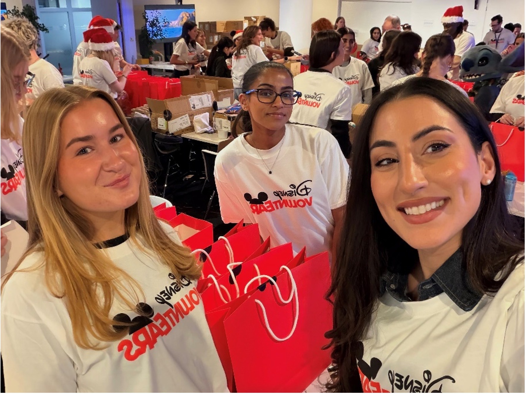 Disney UK employees and apprentices volunteering together, packing gift bags for charity during a company community initiative.