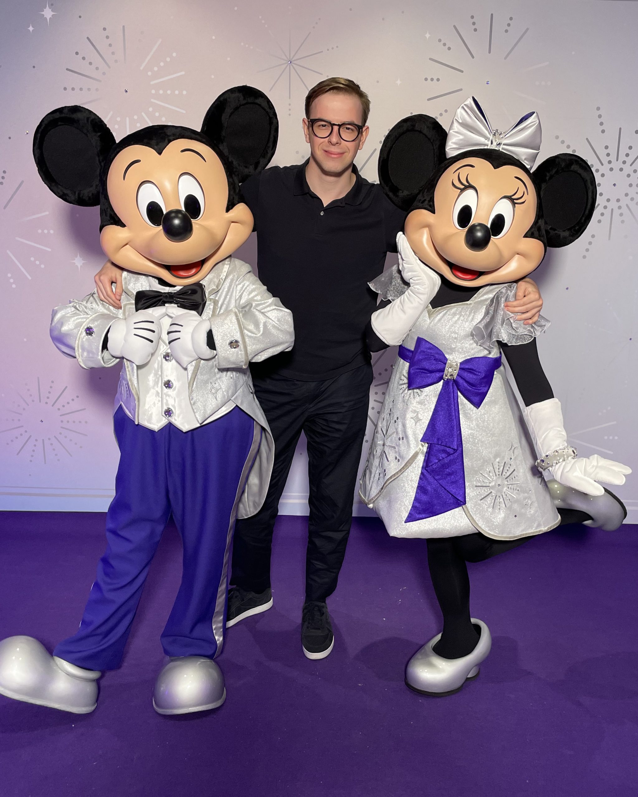 Disney employee photographed with iconic Disney characters at a company event, illustrating the culture and career opportunities highlighted in the Life at Disney early‑careers blog.