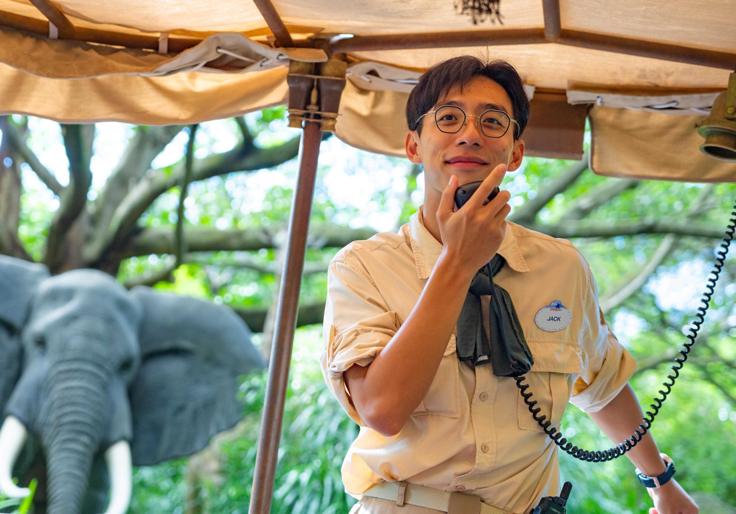 Image of Jungle River Cruise skipper speaking into microphone with elephant animatronic in the background