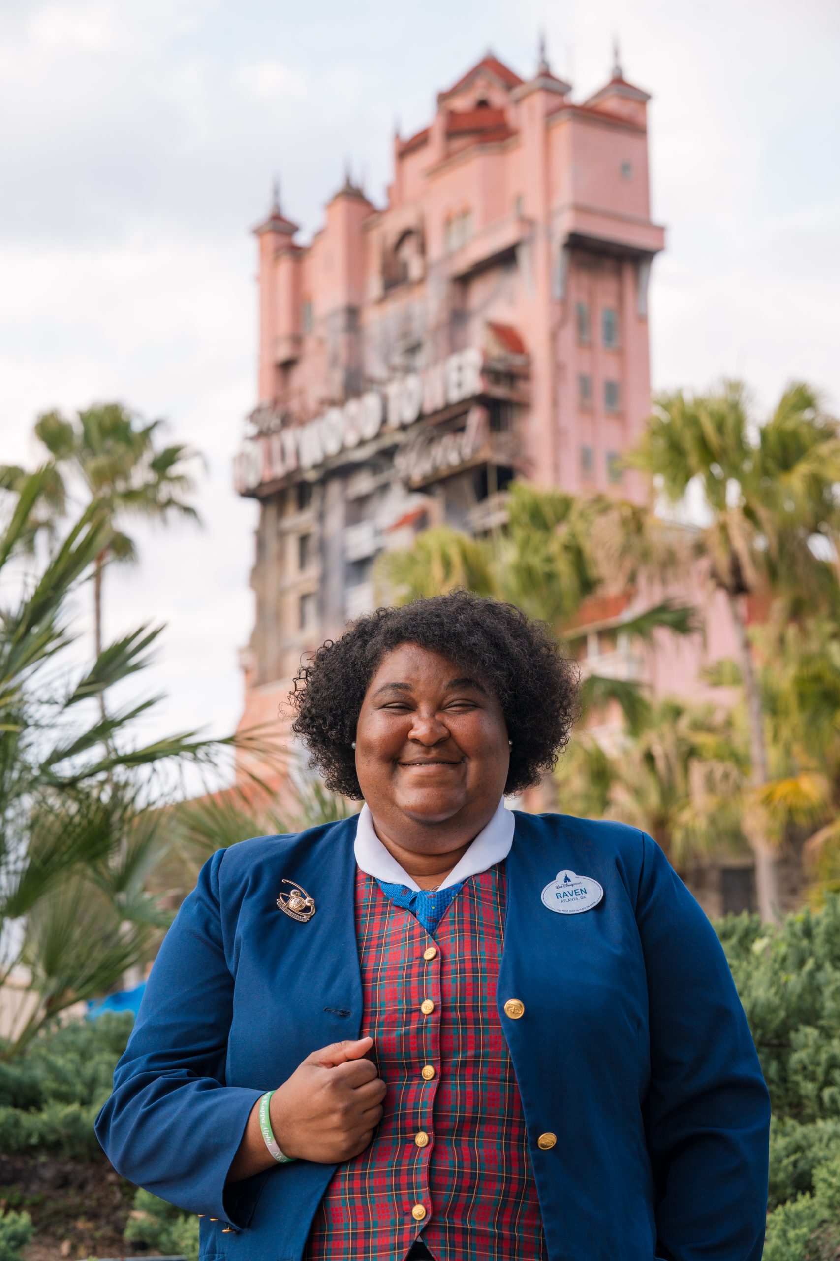Guest Relations cast member holding her jacket and smiling in front of The Twilight Zone Tower of Terror&trade;.