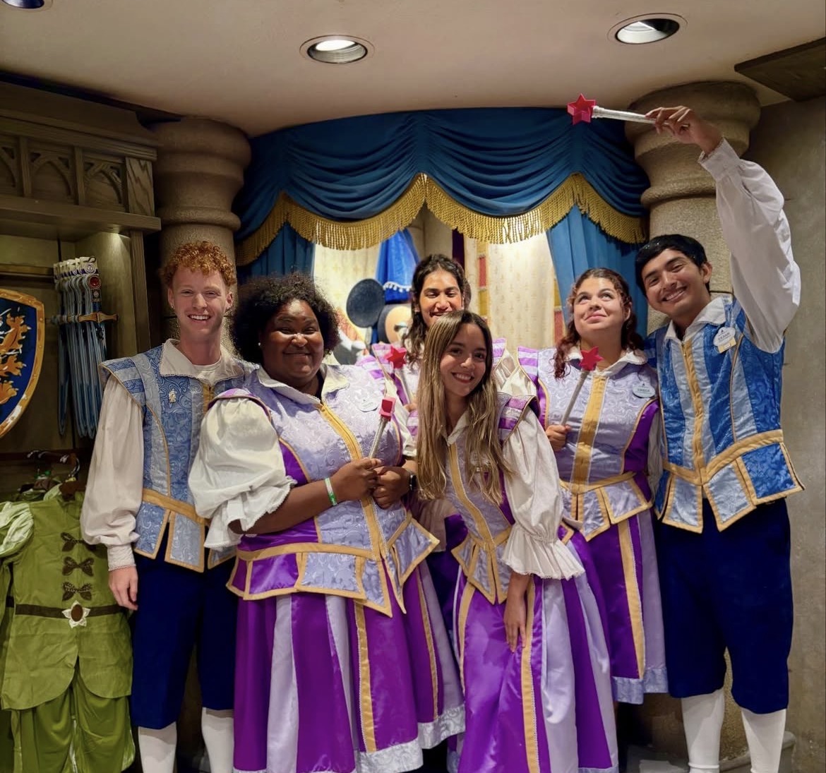 Male and female Fantasyland Merchandise cast members smiling for group picture.