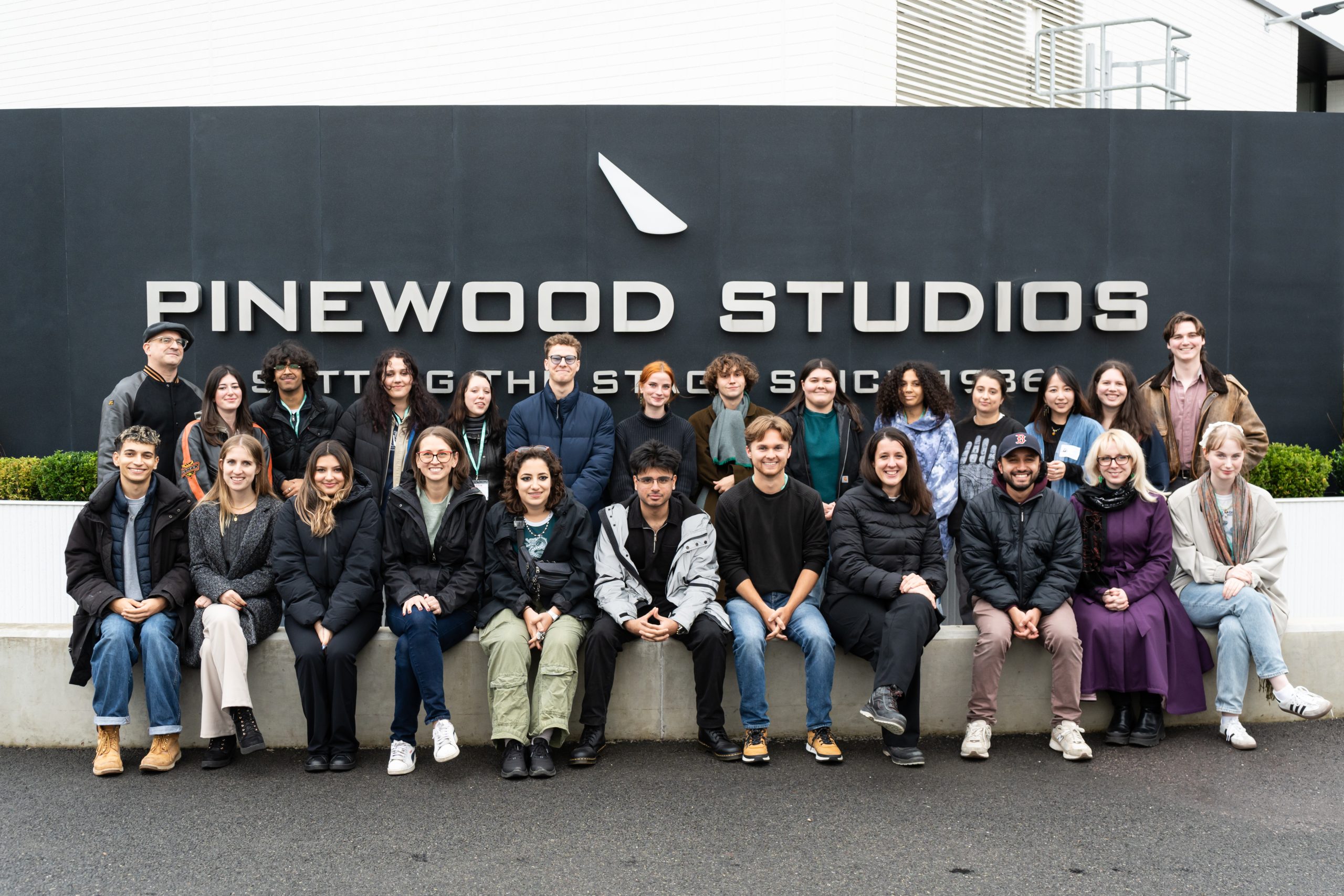 Group photo of Anna and the Disney Crew Academy class standing in front of the Pinewood Studios sign.