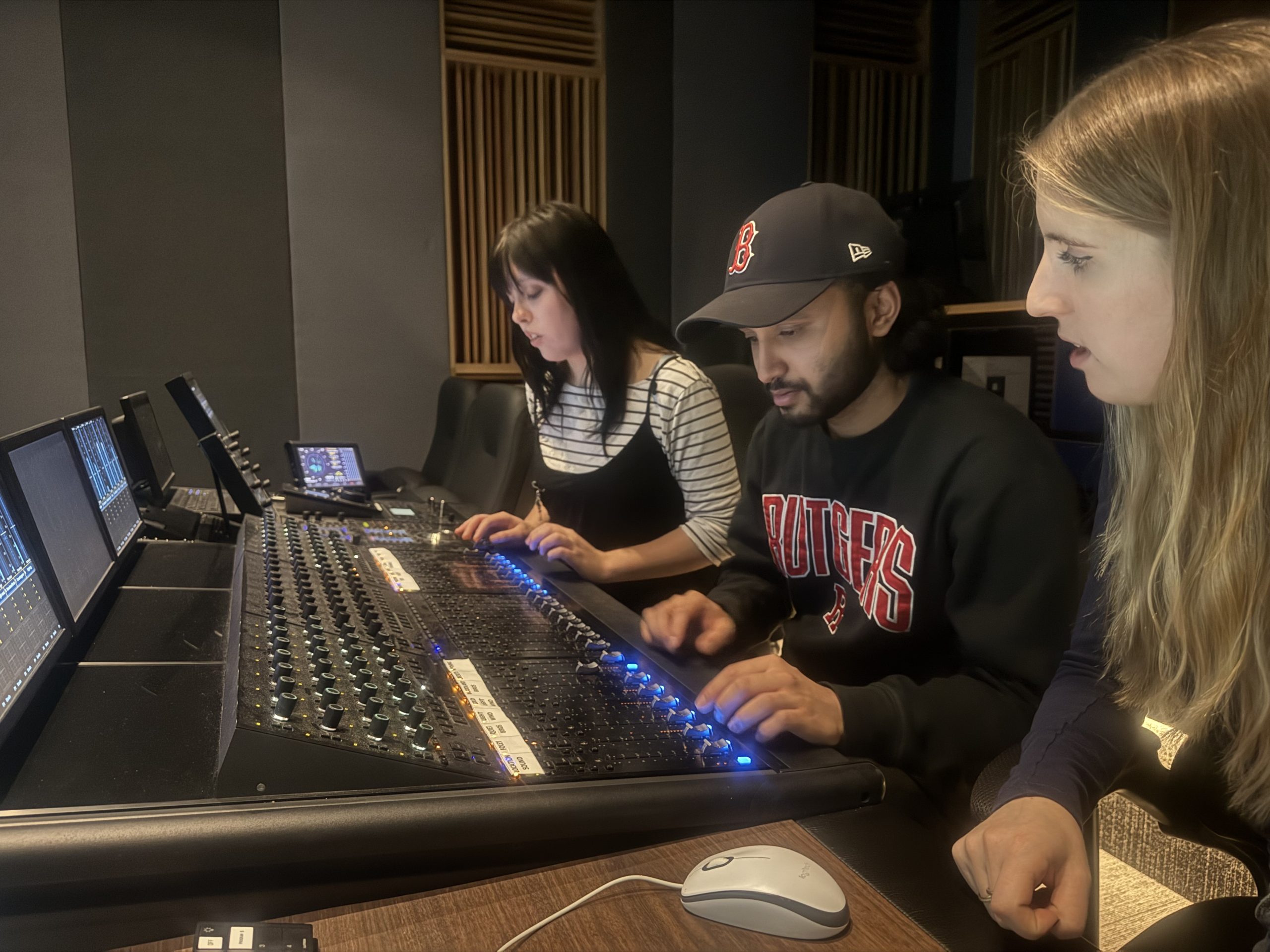 Anna sits at a sound board with two fellow trainees.