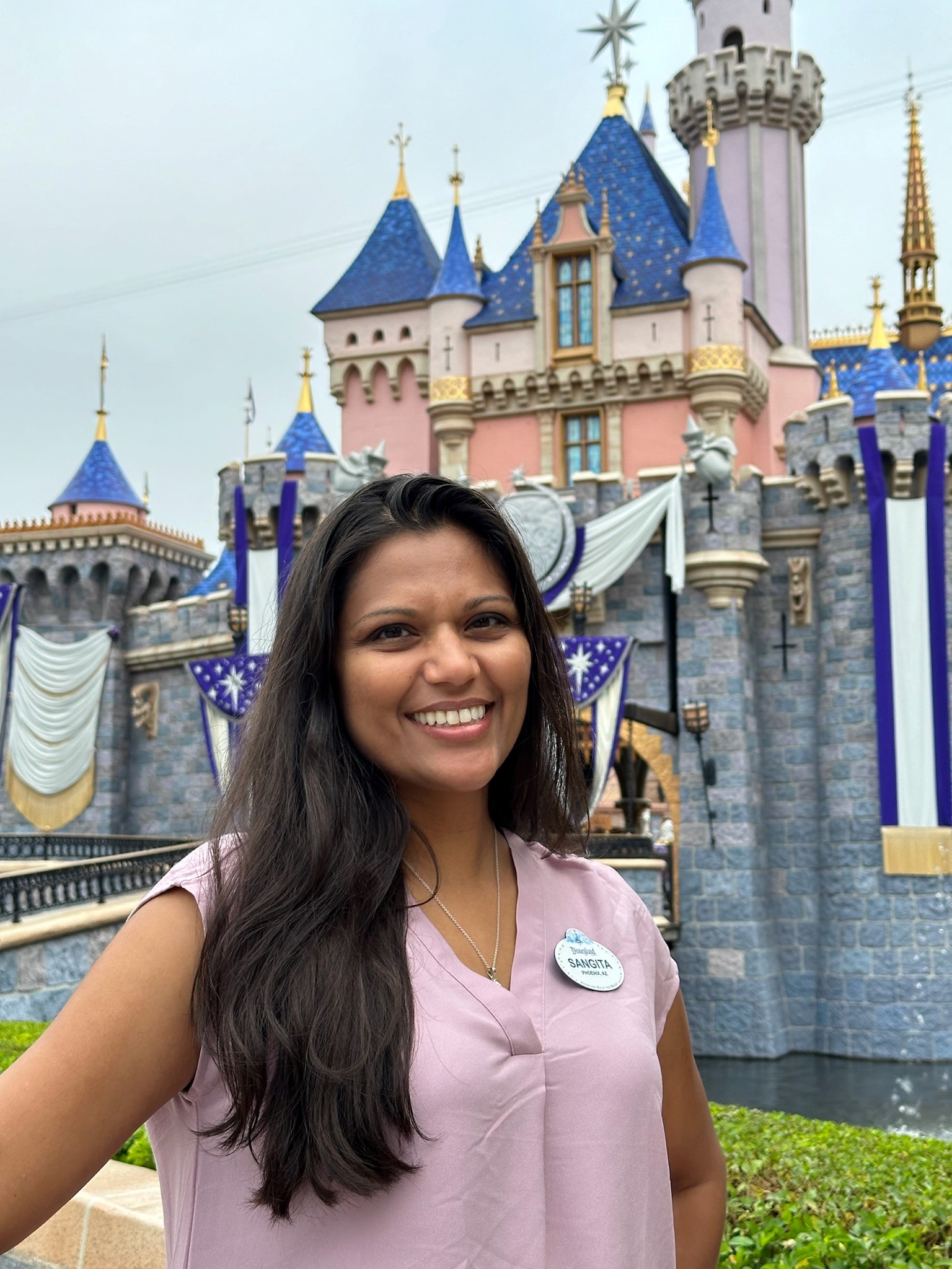 Sangita's headshot in front of castle at Disneyland.