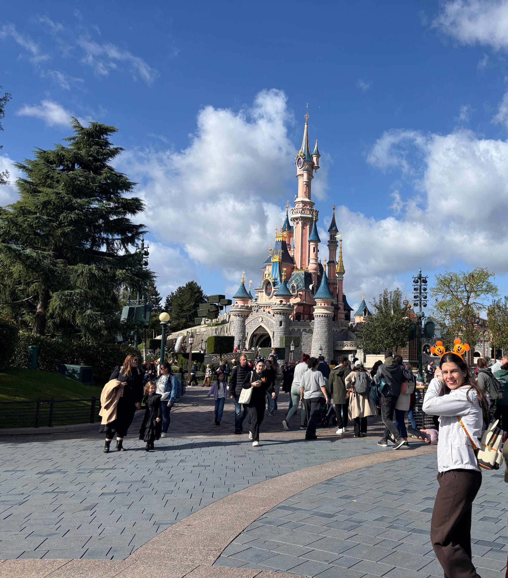 Mariana standing in front of castle at Disneyland Paris wearing Mickey Mouse ears.