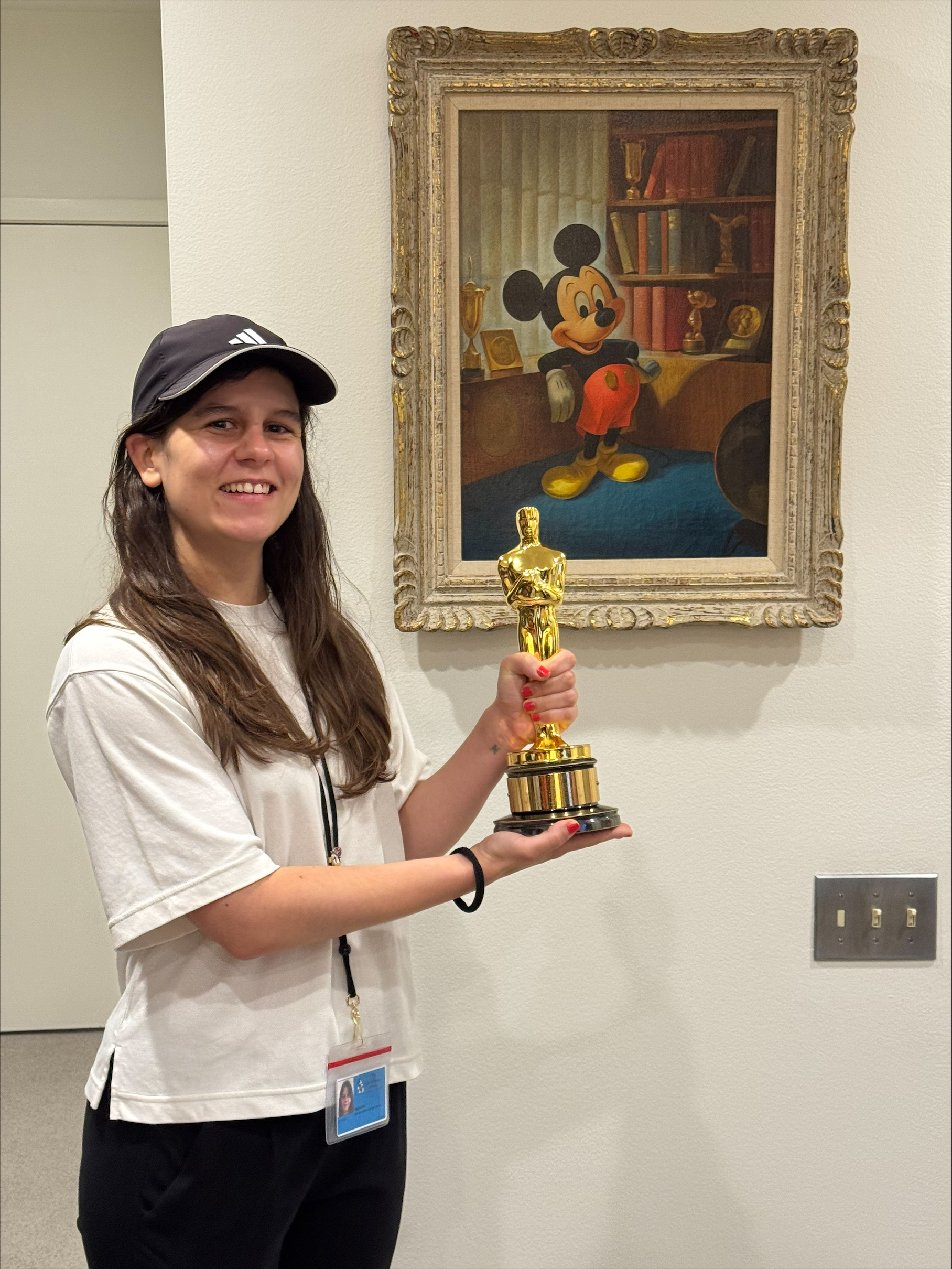Mariana posing with an award she won in front of a Mickey Mouse portrait