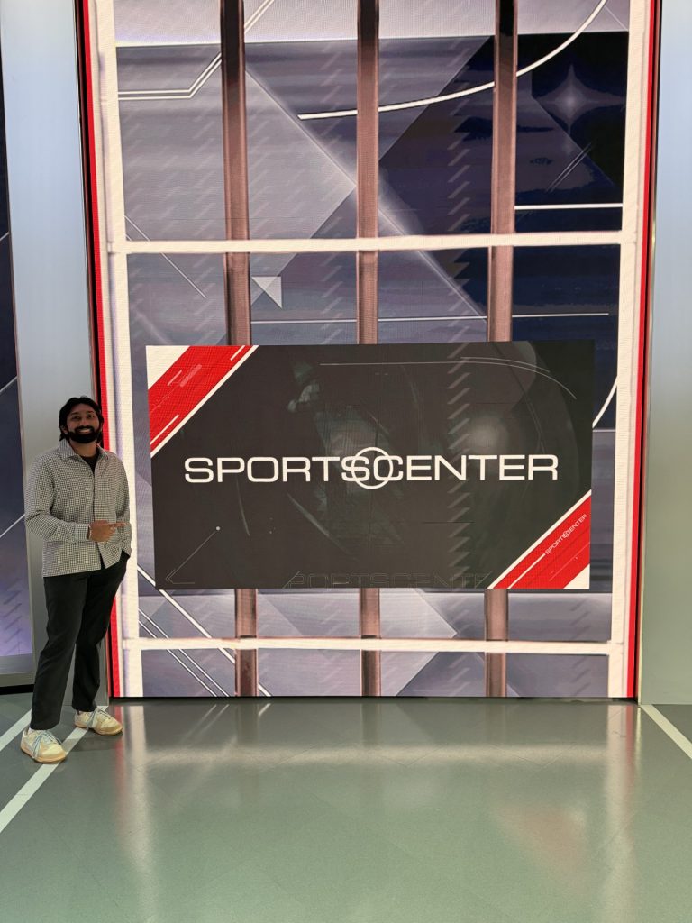 Person pointing at a large &ldquo;SportsCenter&rdquo; display screen inside a modern studio setting.