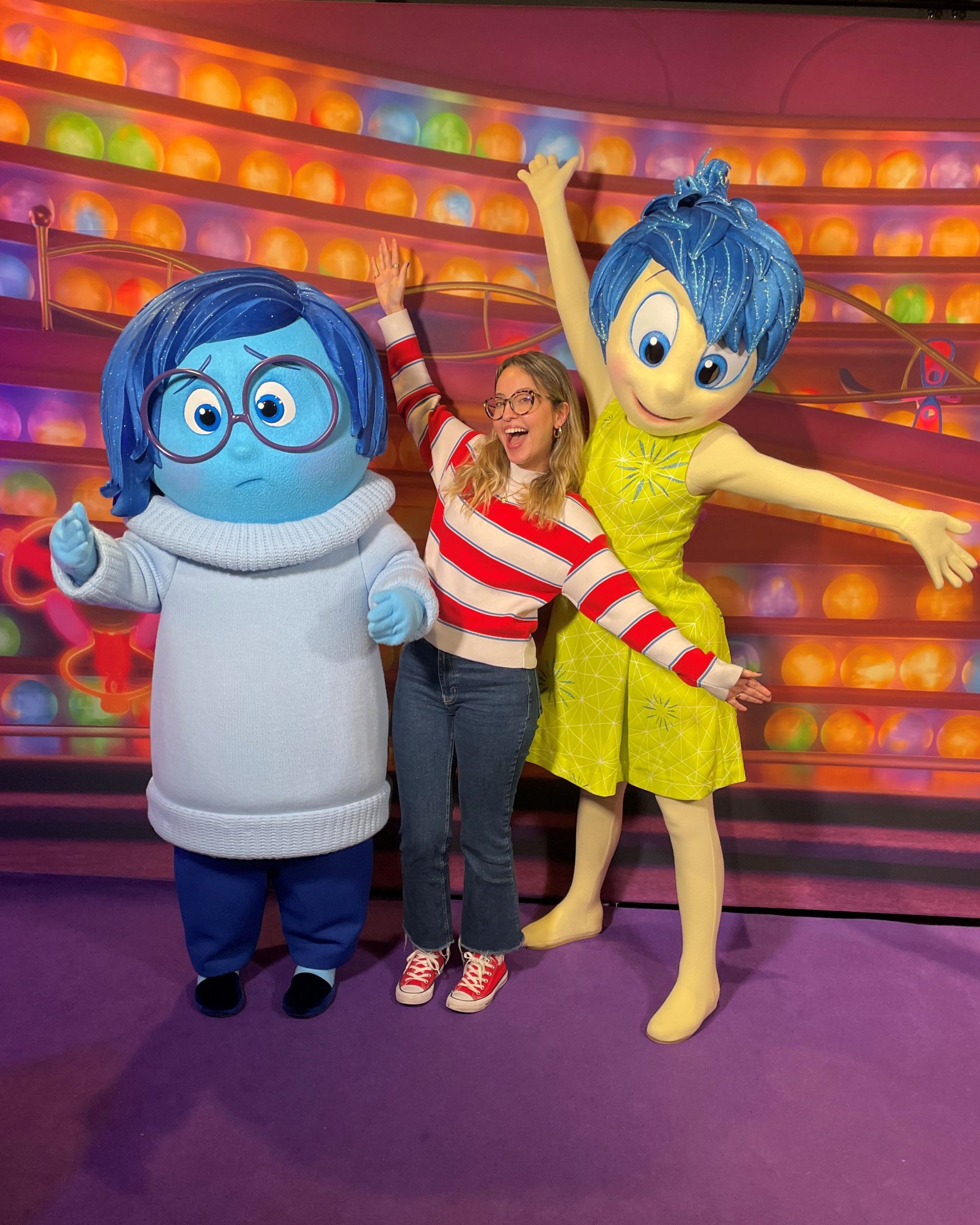 Disney recruiter Sevay poses with Disney and Pixar's Joy and Sadness, reflecting the creativity, storytelling and collaboration that influence careers across The Walt Disney Company.